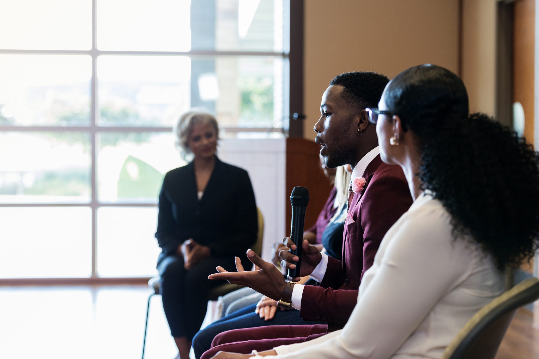 While participating in a panel discussion, a young African American businessman answer's an audience member's question.